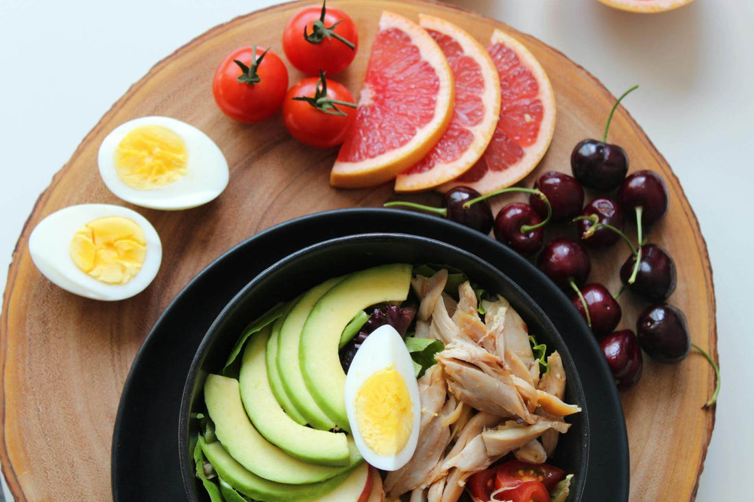 Flat lay of anti-inflammatory foods including avocado, eggs, chicken, and fruit for a healthy meal.